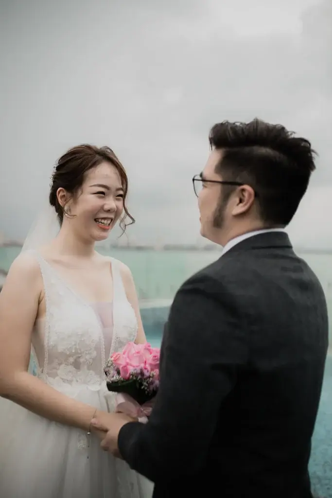 Bride and groom holding hands by the sea under cloudy sky in Penang—captured by wedding photographer Struck By Luna.