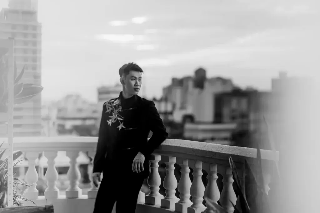 Wedding groom standing on balcony with city skyline in Penang, dressed in floral-embroidered suit—photographed by wedding photographer Struck By Luna.