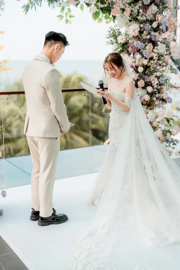 Wedding ceremony in Penang with bride reading vows on floral stage—captured by wedding photographer Struck By Luna.